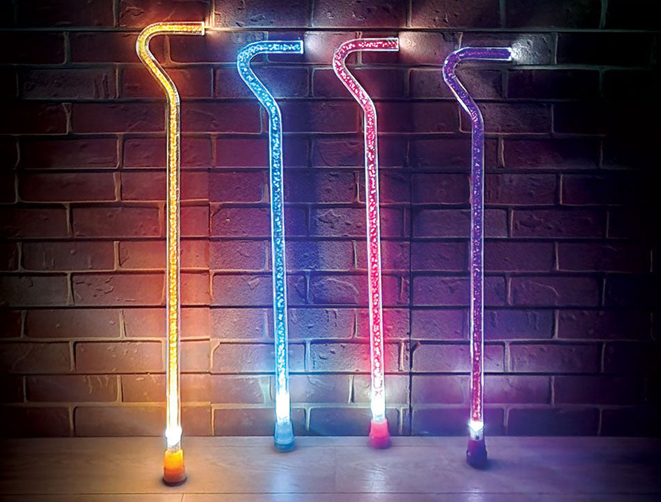 Four colorful LED canes against a brick wall.